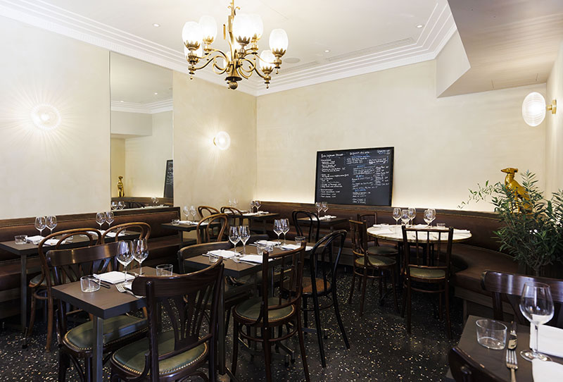 El comedor del restaurante L'Arrêt en París enseña sus mesas, sillas y lámparas clásicas