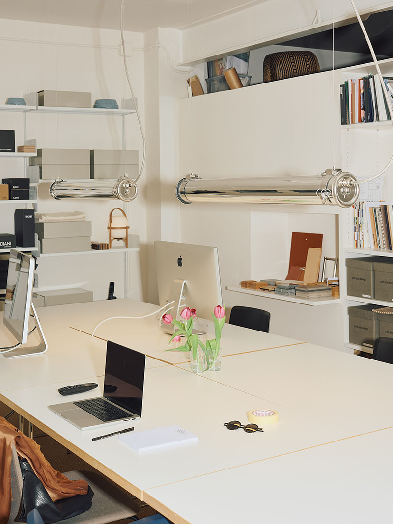 Espacio de trabajo de Matèria, tienda de mobiliario en Barcelona, con mesas blancas y luminarias cromadas