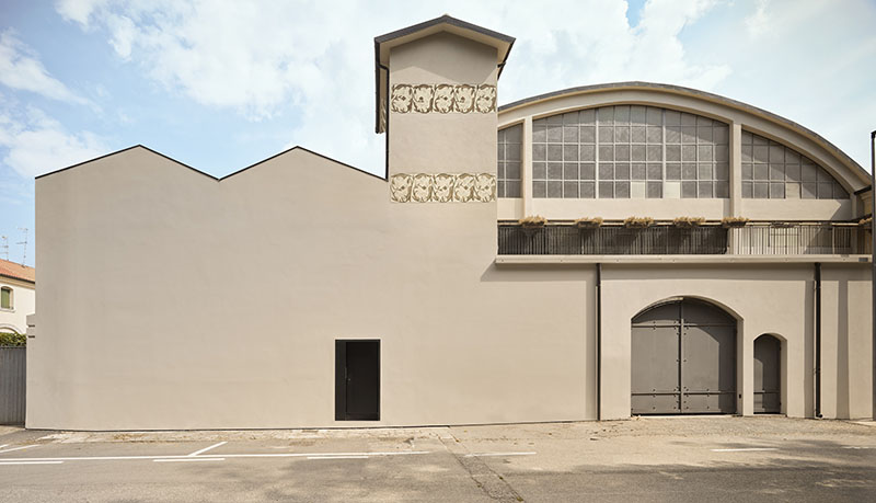 QB Atelier muestra en PDS House la fachada industrial conservada con un muro ciego y una puerta negra