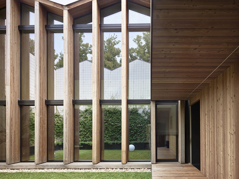QB Atelier estructura en PDS House el patio interior con una envolvente de madera y un frente acristalado vertical