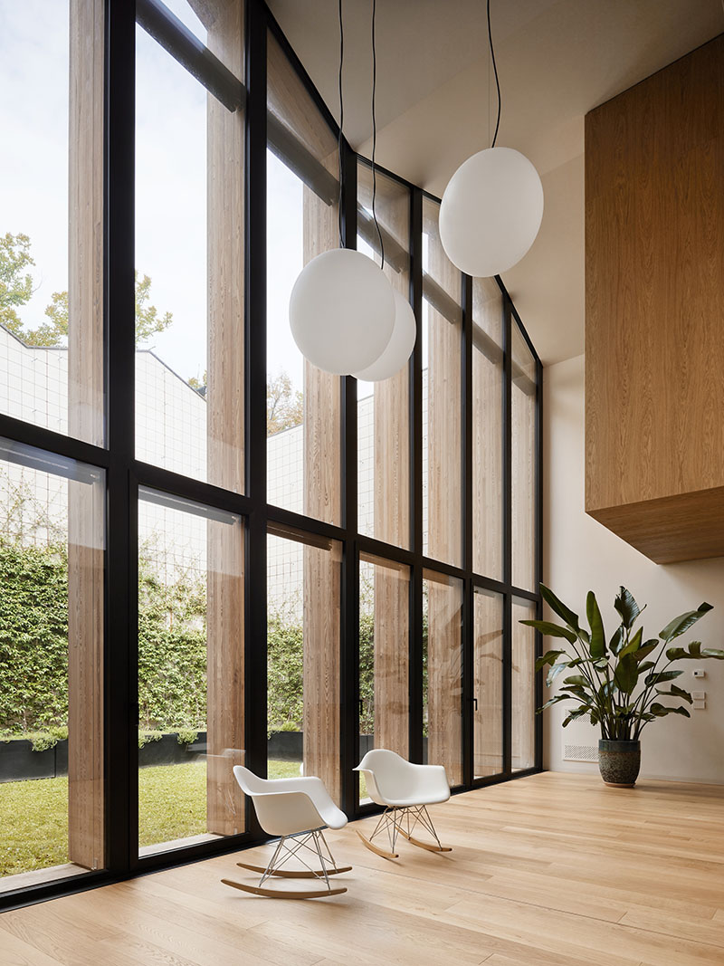 QB Atelier ilumina en PDS House el doble espacio del salón con un frente continuo de vidrio hacia el jardín