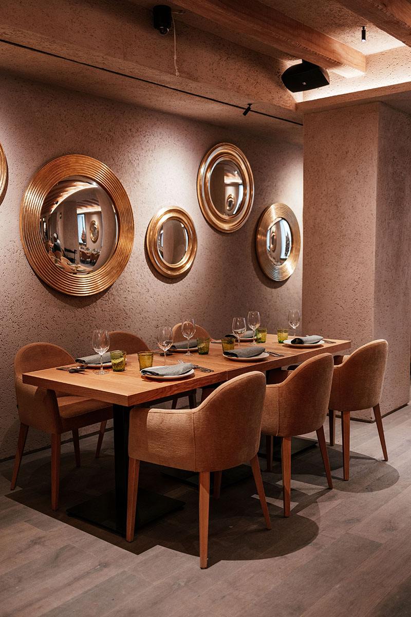 Comedor con mesas vestidas y espejos circulares dorados en El Bajío Madrid