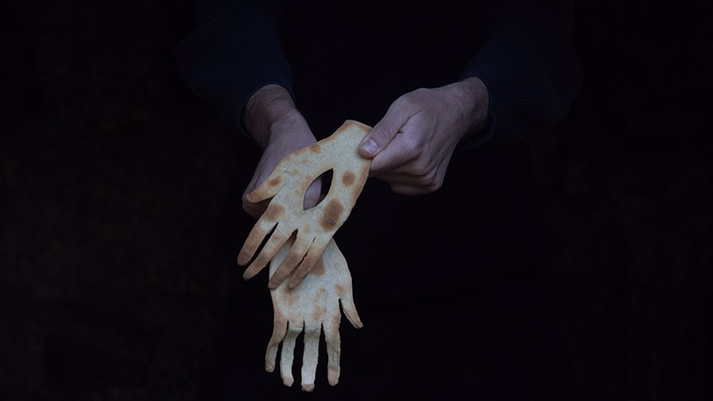 Sara García vincula la hospitalidad a unas manos que sostienen dos piezas en forma de mano elaboradas con pan