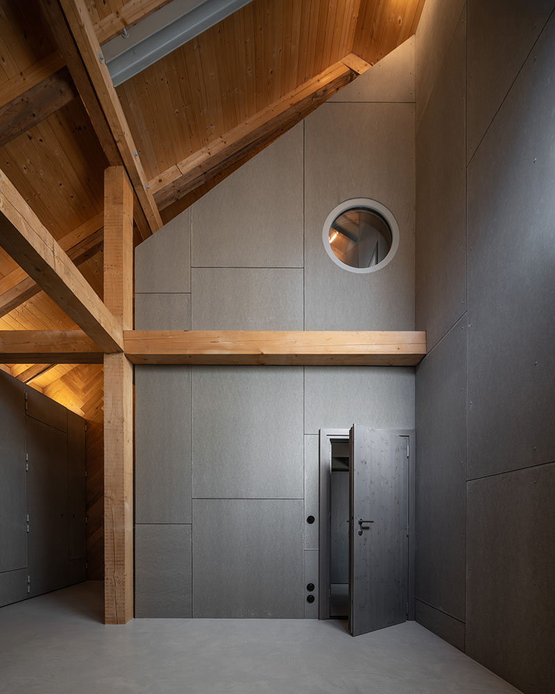 Studio Plyš expone la estructura interior de Casa Borová Lada con paneles grises y vigas de madera vistas