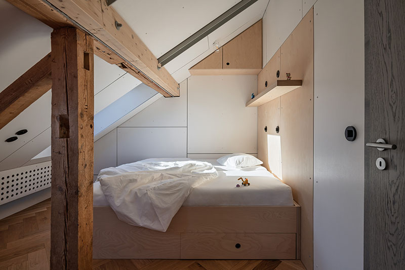 Studio Plyš ordena un dormitorio infantil en Casa Borová Lada con cama de madera y estantes