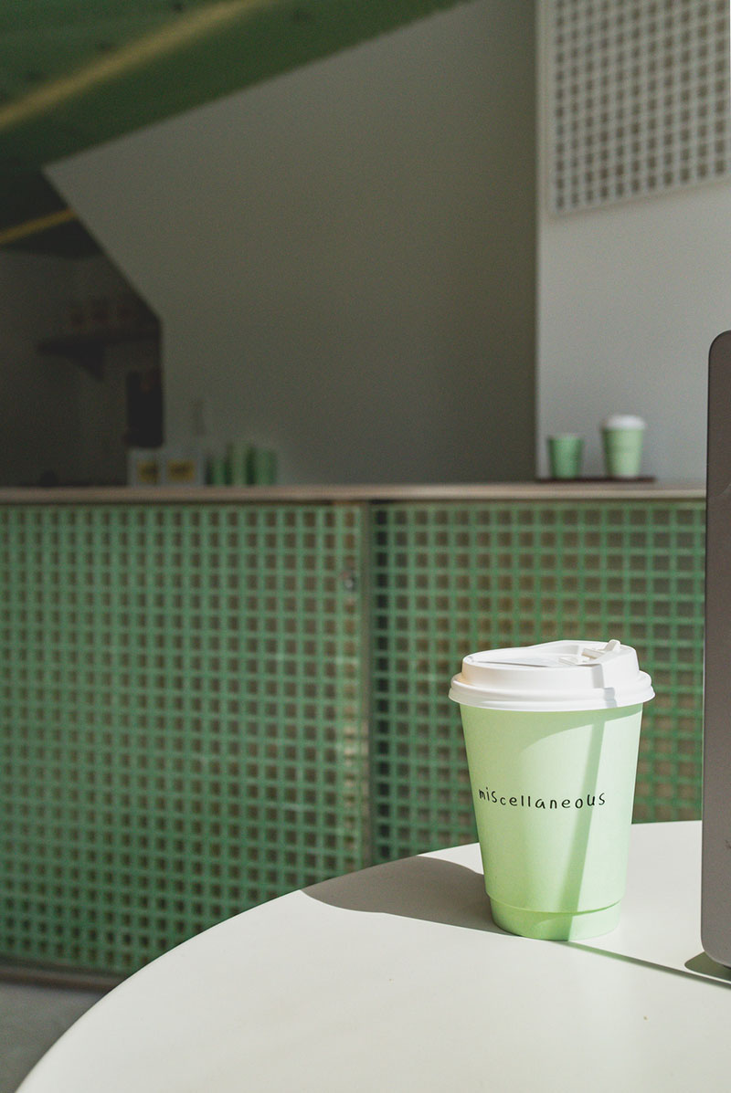 Vaso de café con imagen de la barra al fondo en Misc Coffee, StudioAC