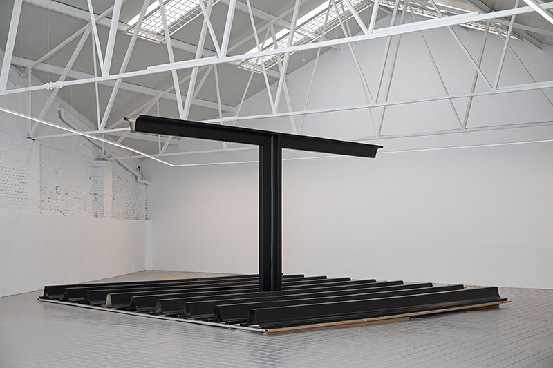 Estructura base de Telas Armadas de Paloma Cañizares formada por un pilar central y perfiles alineados en el suelo de la nave expositiva