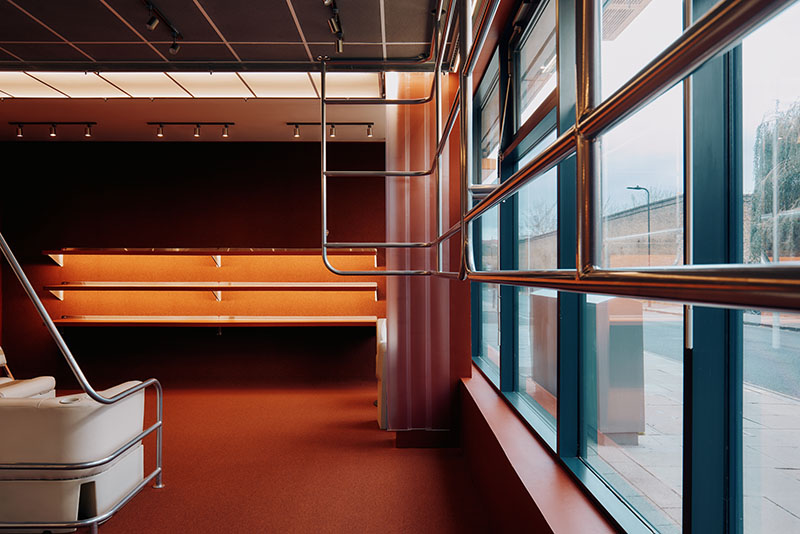 Thiss Studio interiorismo tienda KK London: espacio con pasamanos de barco y sofás de cuero blanco