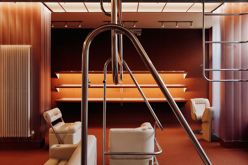 Thiss Studio interiorismo tienda KK London: espacio con pasamanos de barco y sofás de cuero blanco