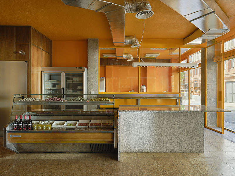 Interior de Central de Pastas diseñado por Codoo Studio con mostrador de granito y vitrina refrigerada