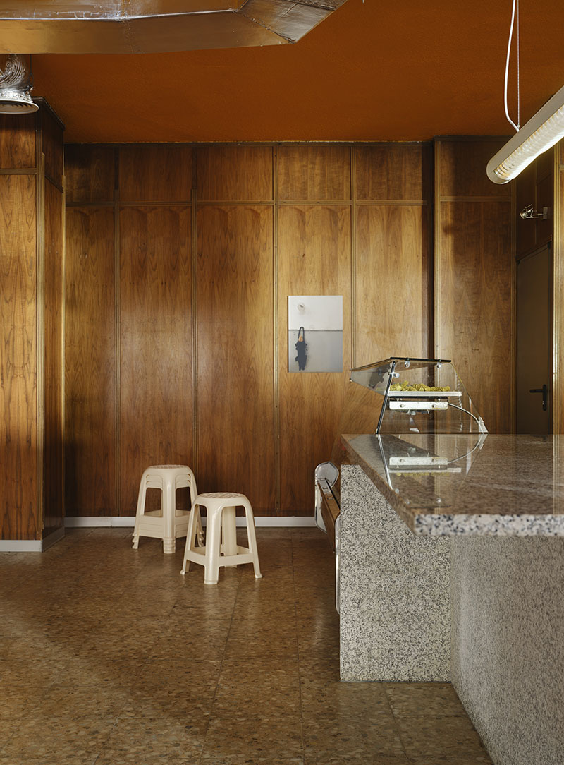 Zona de atención de Central de Pastas con paneles de madera y mobiliario seleccionado por Codoo Studio