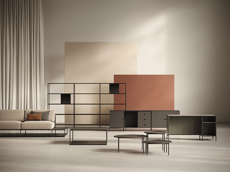 Doi muestra el sistema D1 en una composición con sofá, estanterías y mesas bajas dentro de un espacio neutro