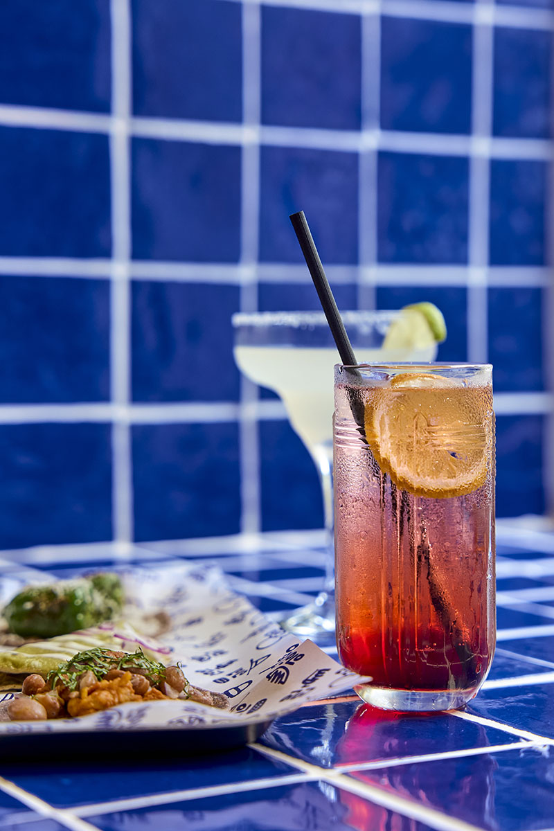 Lolo Taco Bar y Carne muestran un cóctel y un margarita junto a tacos sobre azulejo azul