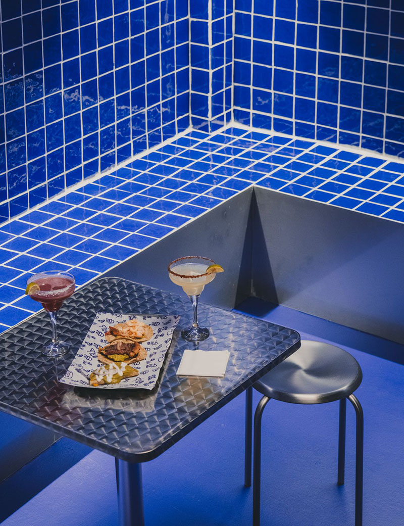 Lolo Taco Bar y Carne exhiben una mesa metálica con tacos y cócteles en la sala azul