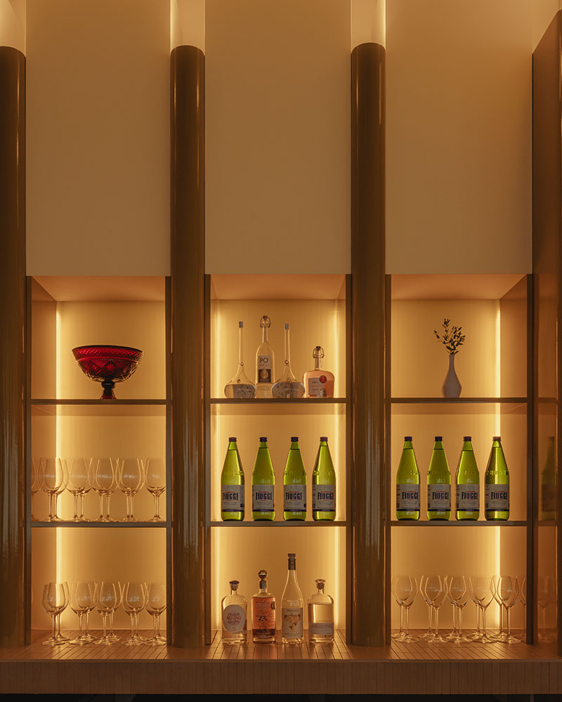 Ste Marie ilumina en Mimi una estantería con botellas, copas y piezas decorativas