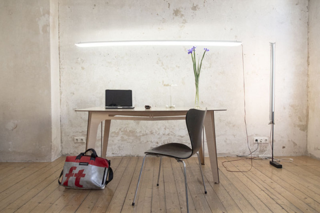 Mesa, silla de trabajo y dos modelos de lámpara Blow, uno de pie, vertical y otro colgado sobre la mesa