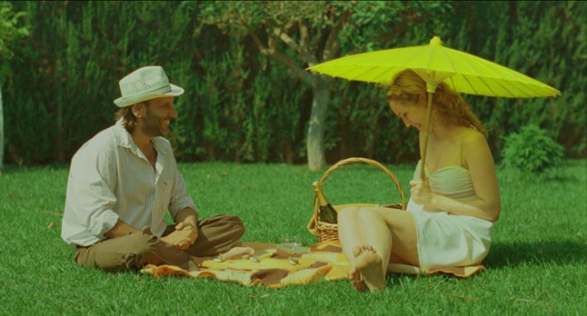 una pareja hacen picnic en un parque, el hobre lleva un sombrero, la mujer una sombrilla verde, colores pastel